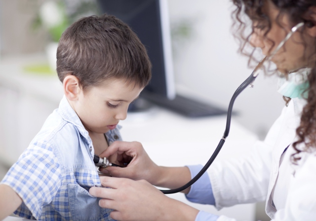 Young friendly female doctor examining a little boy